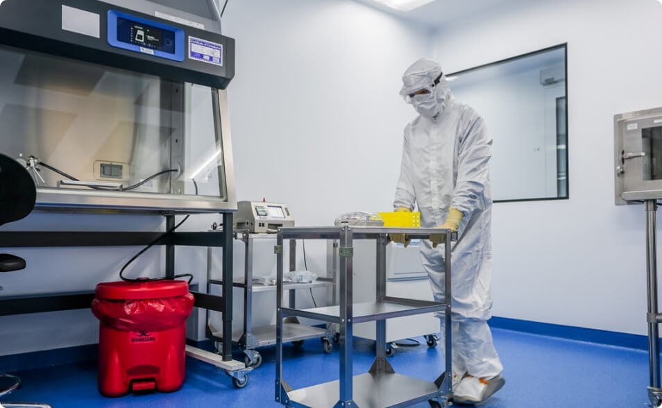 Lykan worker moving equipment in a cGMP cell therapy processing suite.