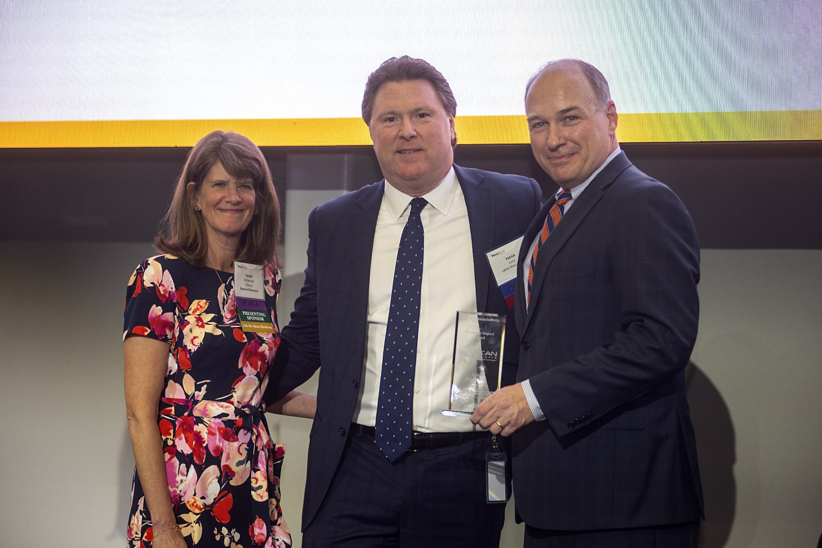 Patrick Lucy, Lykan Bioscience CEO, accepting Mass Impact award with woman to his right and man to his right.