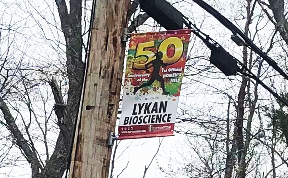 Lykan's sponsorship banner for the 2022 Boston Marathon, hung on a tree outside on the path of the race.
